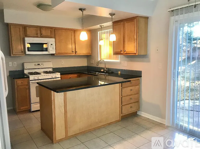 A kitchen with wooden cabinets and a black countertop.