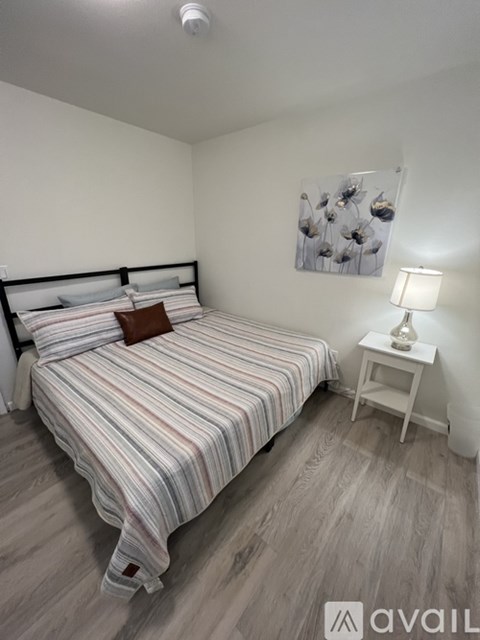 A bedroom with a bed, nightstand, and lamp.