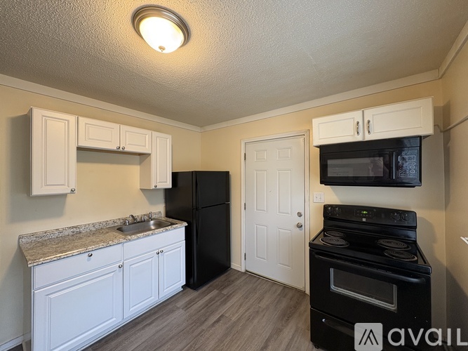 A kitchen with black appliances and white cabinets.