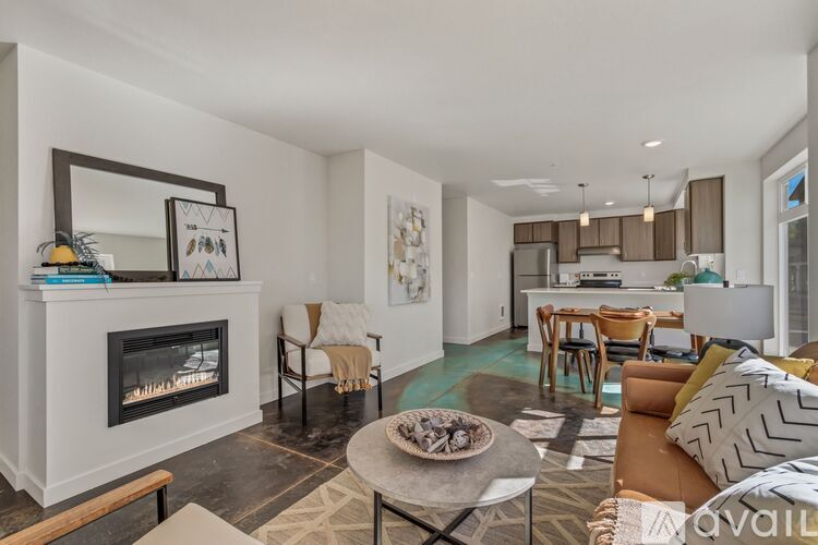 A modern living room with a fireplace and a dining area in the background.
