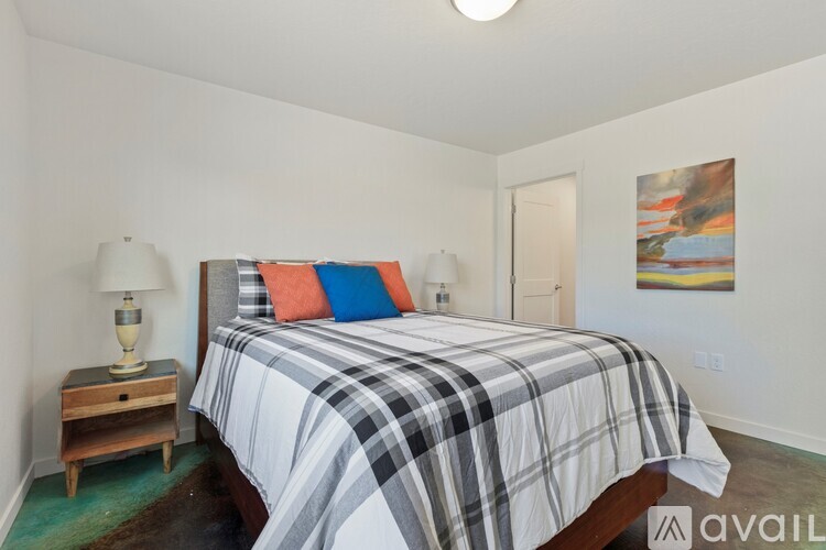 A bedroom with a bed, nightstand, and a painting on the wall.