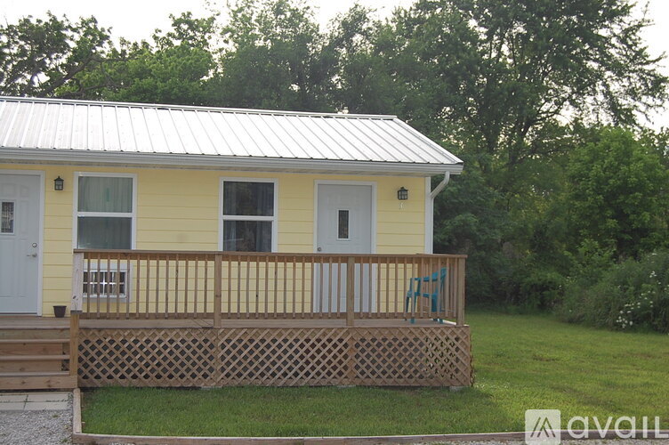 A yellow house with a metal roof and a wooden fence.