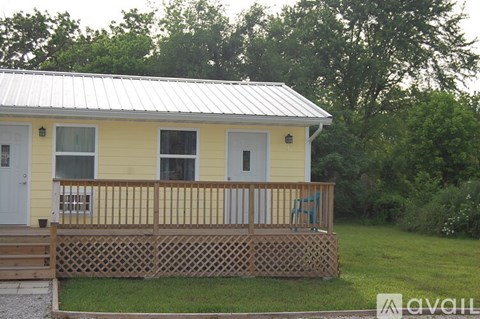 A yellow house with a metal roof and a wooden fence.
