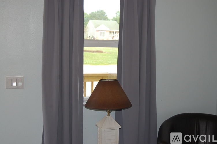 A lamp on a table in front of a window with curtains.