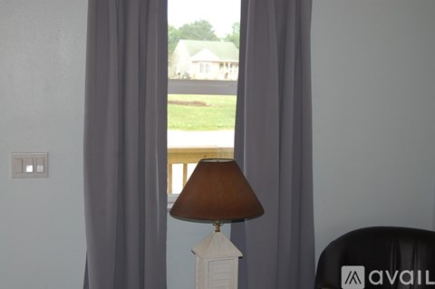 A lamp on a table in front of a window with curtains.