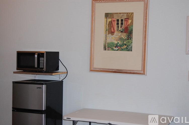 A framed picture hangs on a wall above a microwave and below a stove.