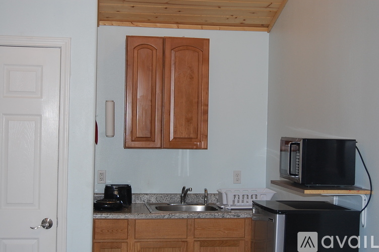 A kitchen with wooden cabinets and a black microwave.