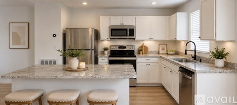 A kitchen with white cabinets and a marble countertop.