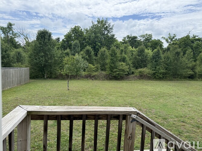 A wooden deck overlooks a grassy field with trees in the distance.