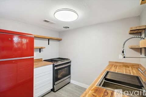 A kitchen with a red fridge and a wooden counter top.