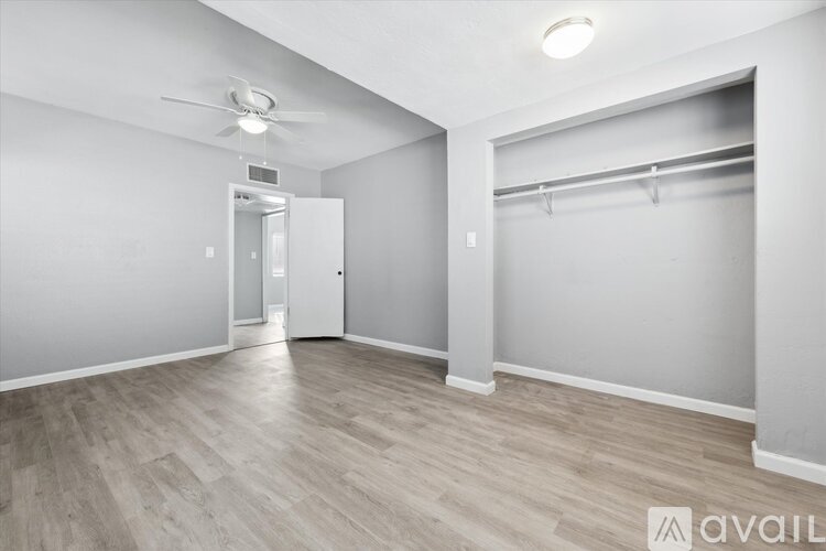 A spacious room with a ceiling fan and a doorway leading to another room.