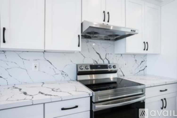 A kitchen with white cabinets and a marble countertop.