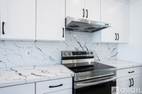 A kitchen with white cabinets and a marble countertop.