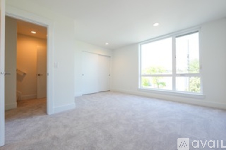 A spacious room with a large window and carpeted floor.