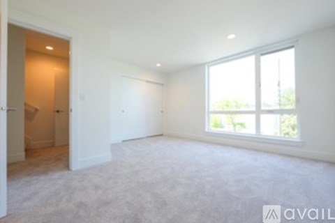 A spacious room with a large window and carpeted floor.