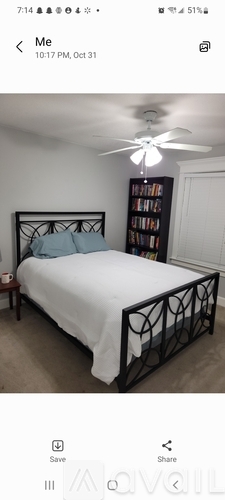 A bedroom with a bed, a ceiling fan, and a bookshelf.