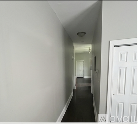 A long white hallway with a door on the right.