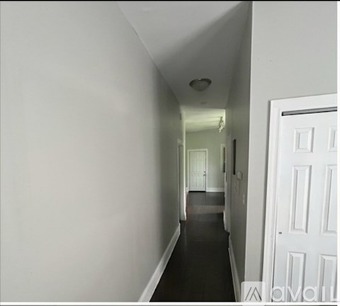 A long white hallway with a door on the right.