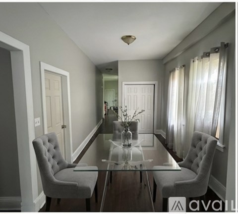 A dining room with a glass table and two chairs.