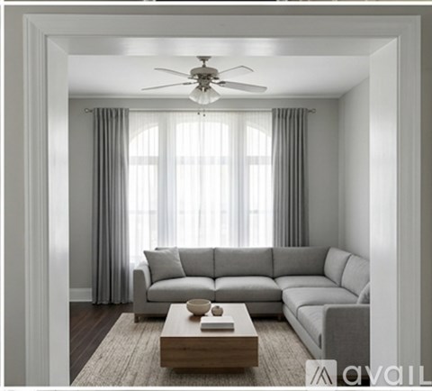 A living room with a grey sofa, a wooden coffee table, and a ceiling fan.