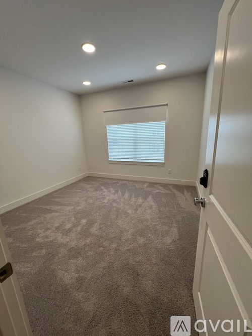 A room with a carpeted floor and a window with blinds.