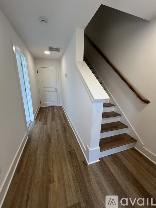 A hallway with wooden floors and a white staircase.