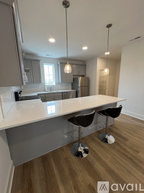 A kitchen with a white countertop and bar stools.
