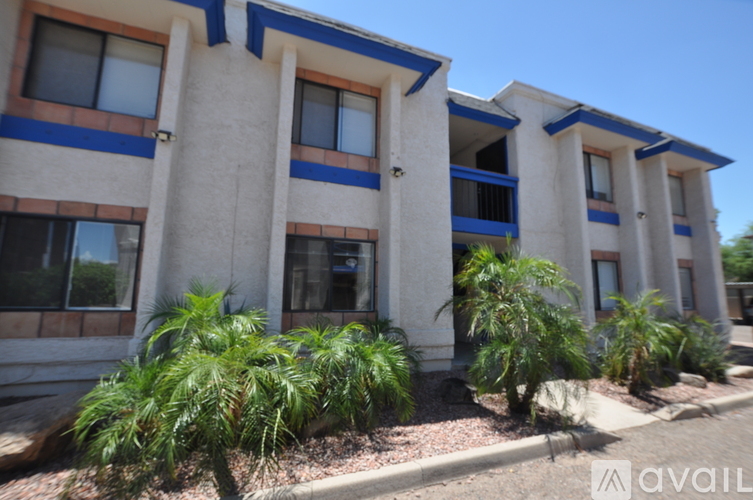 A building with blue trim and windows is surrounded by green plants.