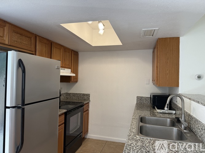 A kitchen with a refrigerator, microwave, sink and cabinets.