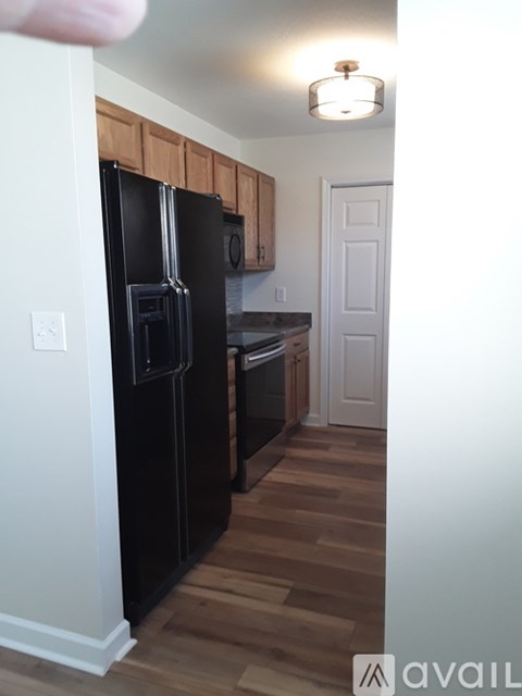 A black refrigerator in a kitchen with wooden cabinets.