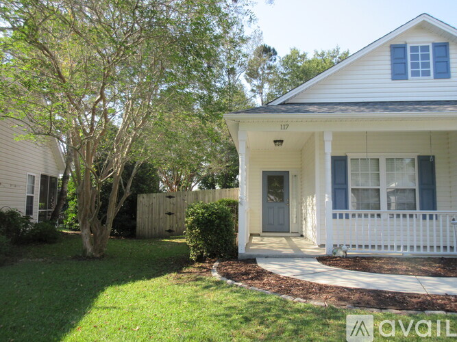 A house numbered 117 with a white porch and a tree in front.