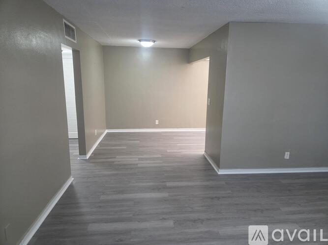 A spacious room with wooden flooring and white walls.