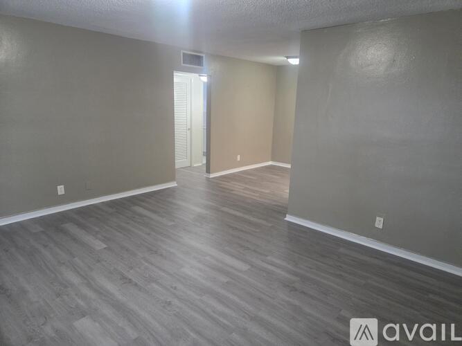 A room with wooden flooring and a door in the background.