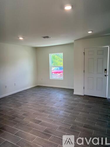 A room with a large window and a door is available for rent.