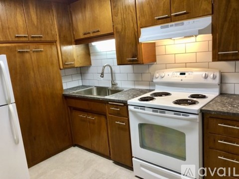 A kitchen with wooden cabinets and a white stove top oven.