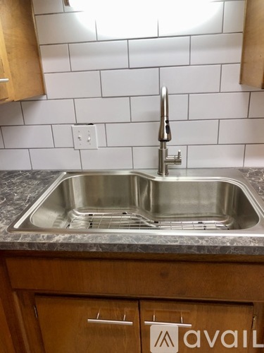A kitchen with a stainless steel sink and wooden cabinets.