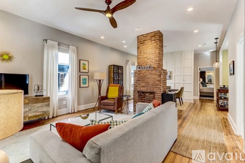 A living room with a grey couch and a brick fireplace.