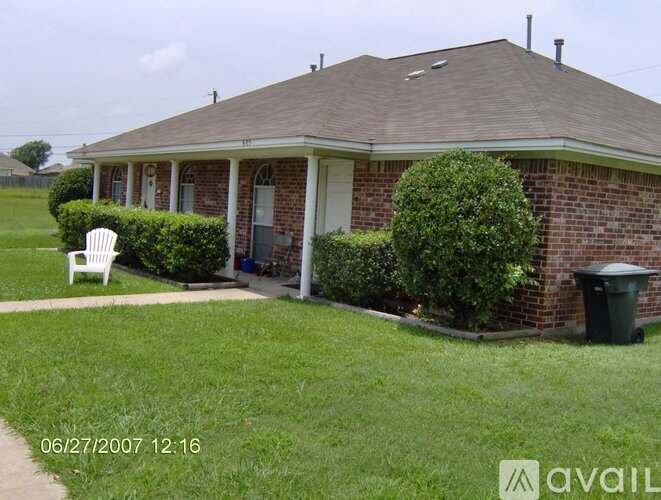 A house with a lawn and a trash can.