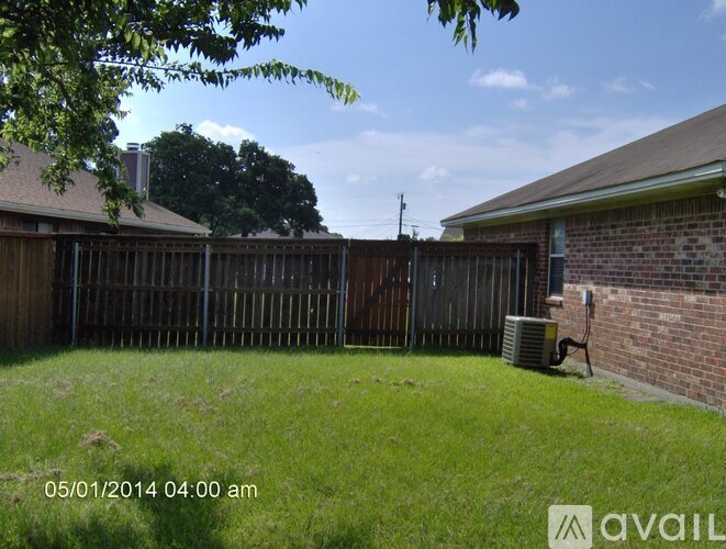 A backyard with a wooden fence and a brick building.
