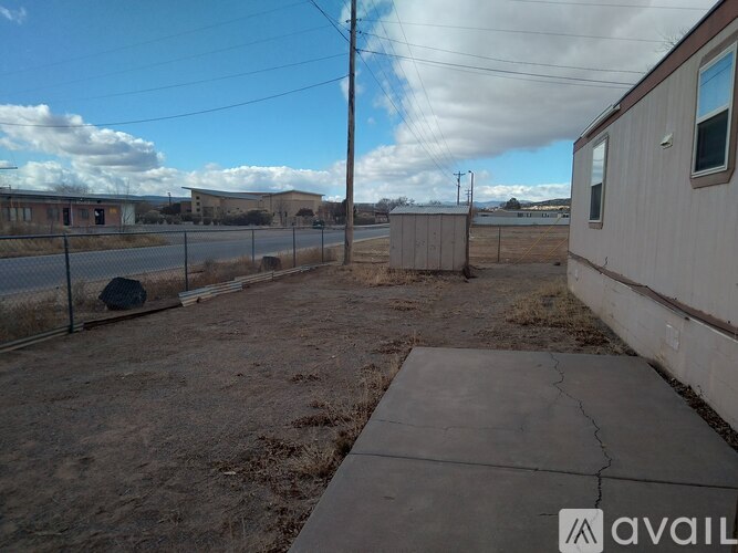 A fenced area with a building to the right and a utility pole in the middle.
