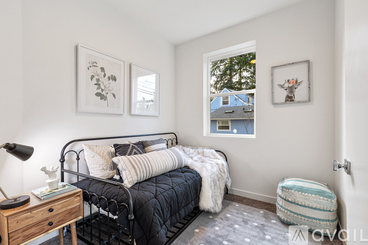 A bedroom with a black metal bed and a wooden nightstand with a lamp on it.