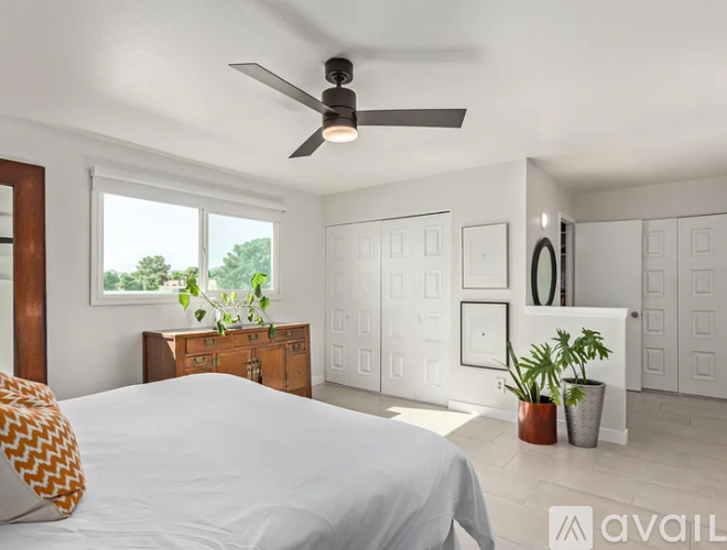 A bedroom with a large bed and a ceiling fan.