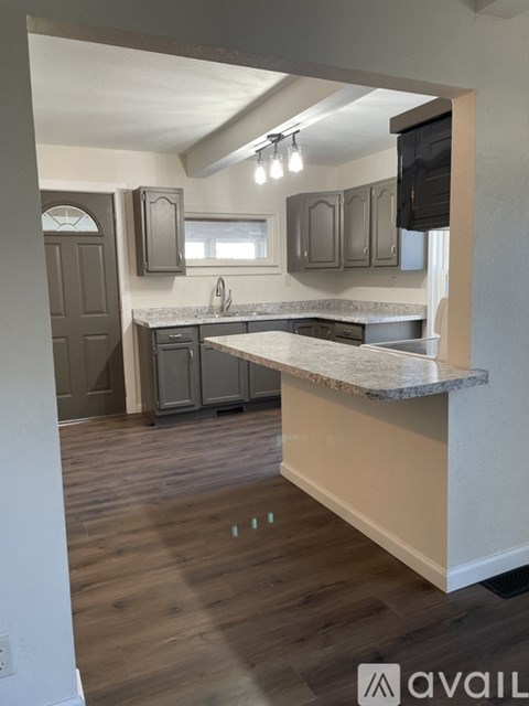 A kitchen with a granite countertop and wooden floors.