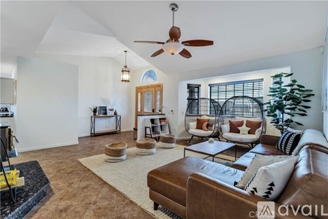 A living room with a brown leather couch and a ceiling fan.