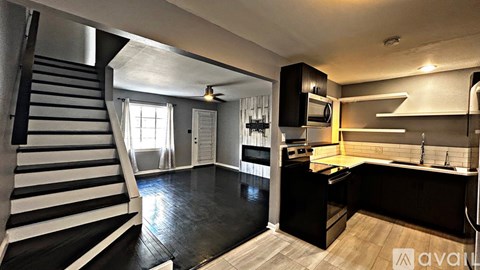 A modern kitchen with dark wood floors and a staircase with black and white stripes.