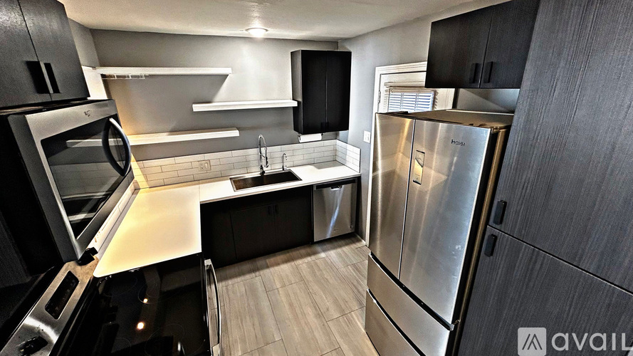 A modern kitchen with stainless steel appliances and black cabinets.
