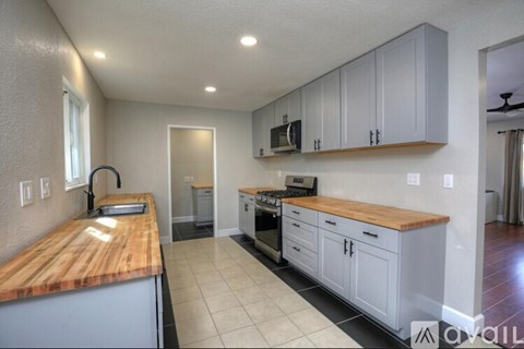 A kitchen with a wooden counter top and white cabinets.