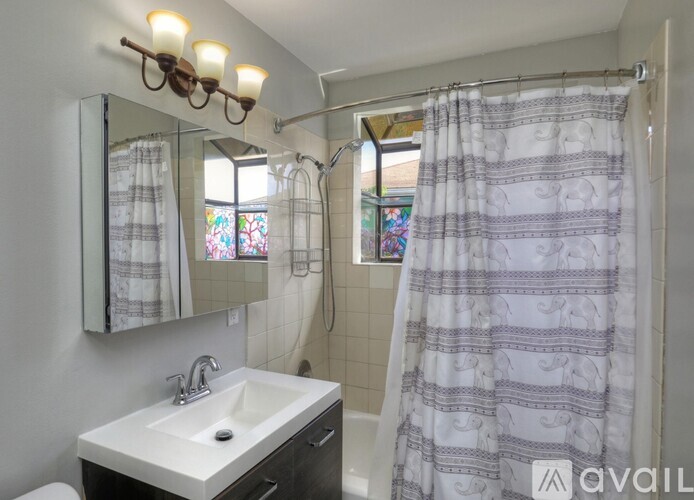 A bathroom with a sink, mirror, and shower.