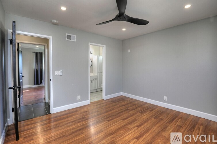 A room with a ceiling fan and wooden flooring.
