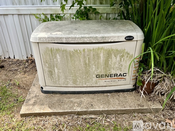 A dirty old Generac gasoline powered generator sits on a concrete slab.